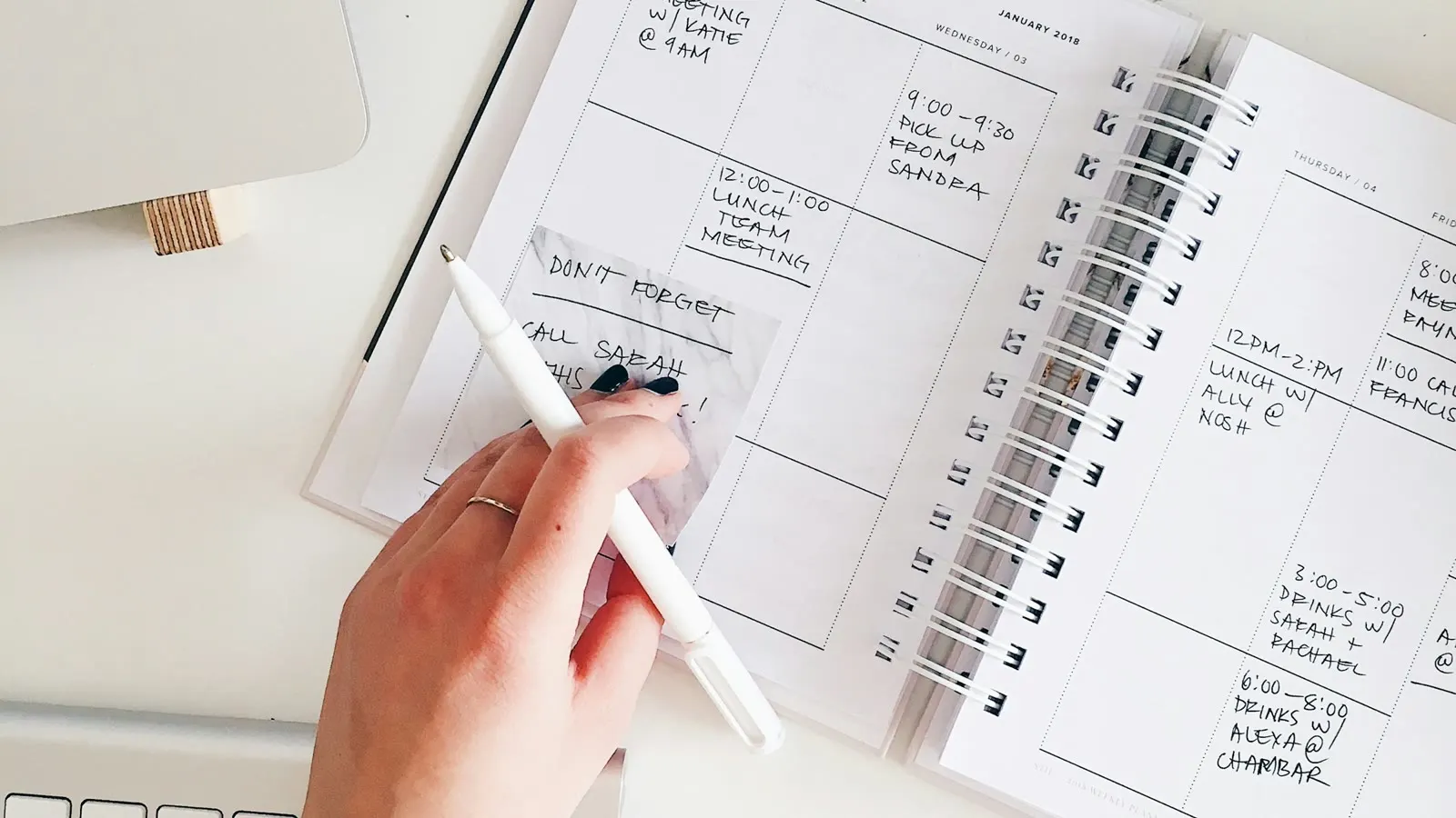 A hand writing dates in a spiral-bound planner