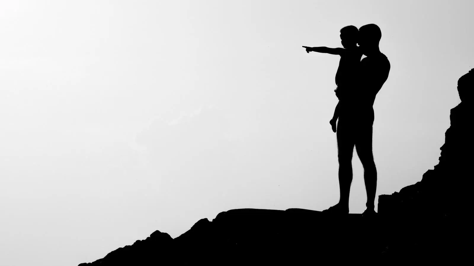 A caregiver and child standing together on a hill